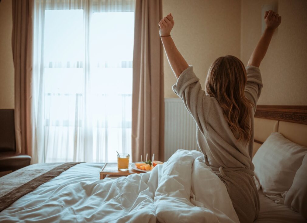 Woman stretching body after awakening on a hotel bed