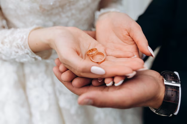 The groom holds the hands of the bride, in which there are two wedding rings