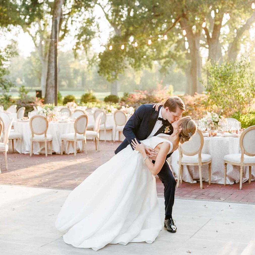 bride and groom kissing in front of outdoor dining tables