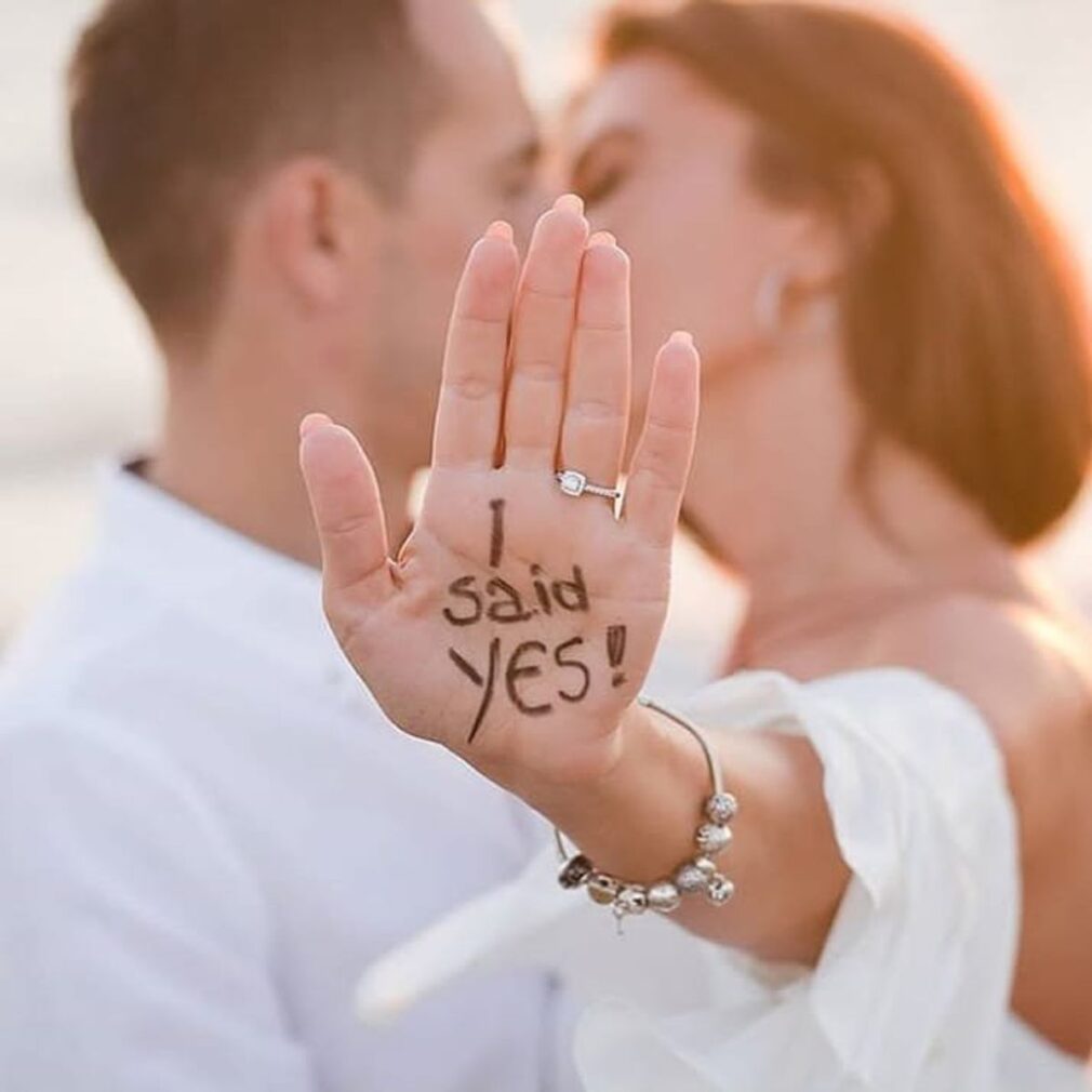 the bride and groom kiss, she shows her wedding ring with "I said Yes" written on the palm of her hand