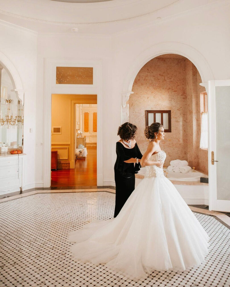 mother adjusts the bride's bodice from the back