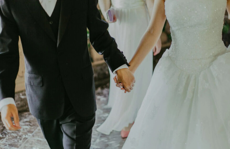 A close-up of a bride and groom's hands as they walk side by side