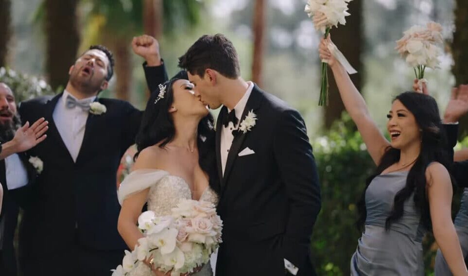 A bride and groom kiss amidst a celebratory moment, wedding guests