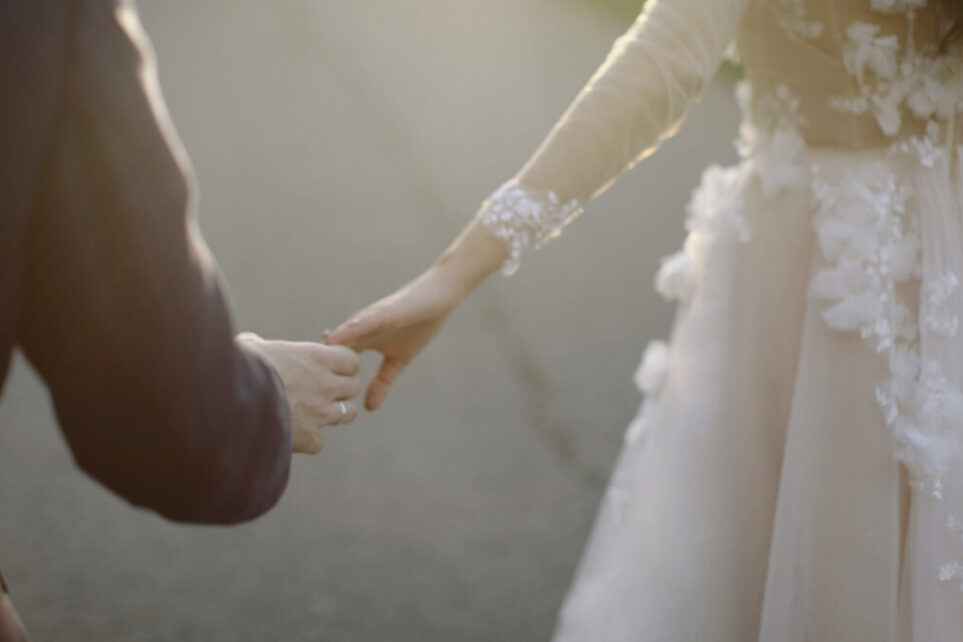The sun on the hands of the bride and groom as they hold hands