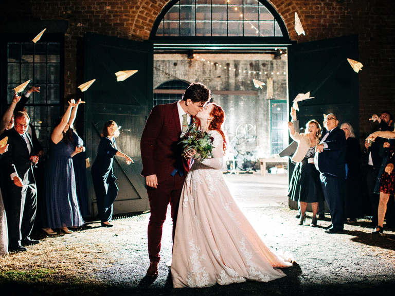 bride and groom kissing in front of guests who throw origami paper cranes