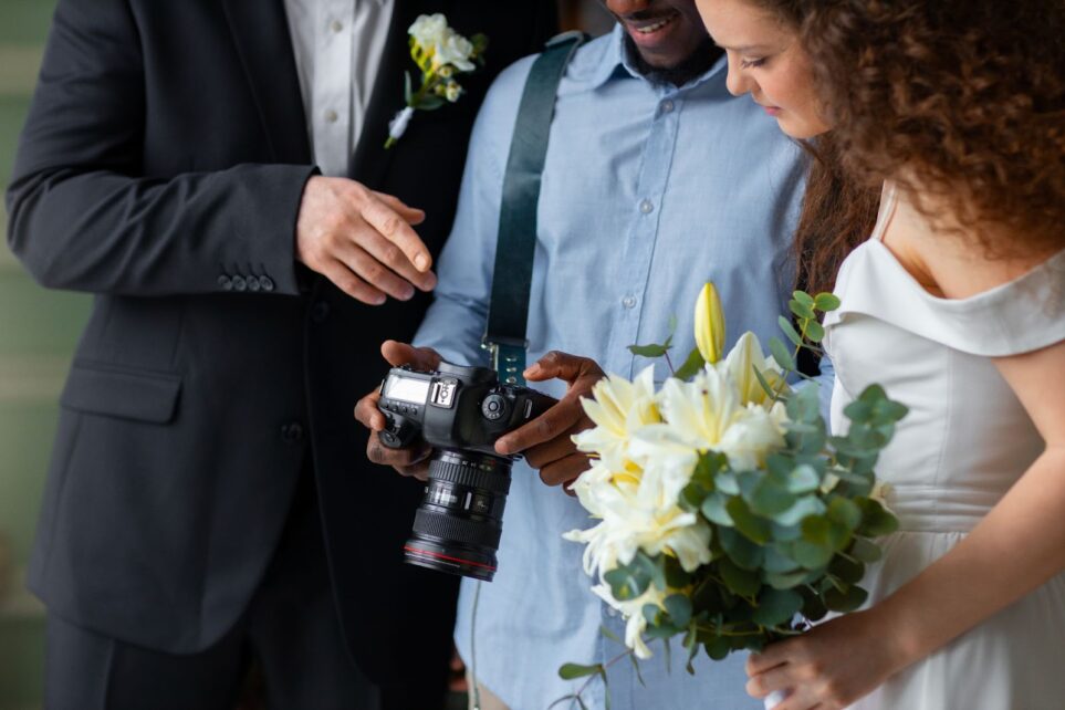 Side view of photographer and married couple looking on photo